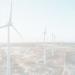 a row of wind turbines next to the ocean